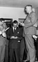 Presidential Assistant John R. Steelman stands on a table to speak to reporters about a railroad strike meeting.